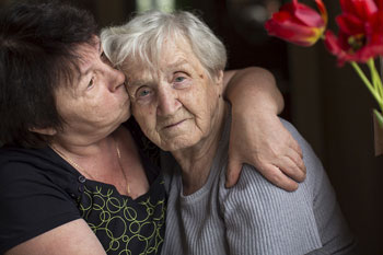 Daughter hugging and kissing elderly ailing parent - MA Health Care Proxy Services